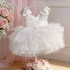 White dress for girls in tulle with bow straps and a layered tutu skirt, front view, for flower girl duties.