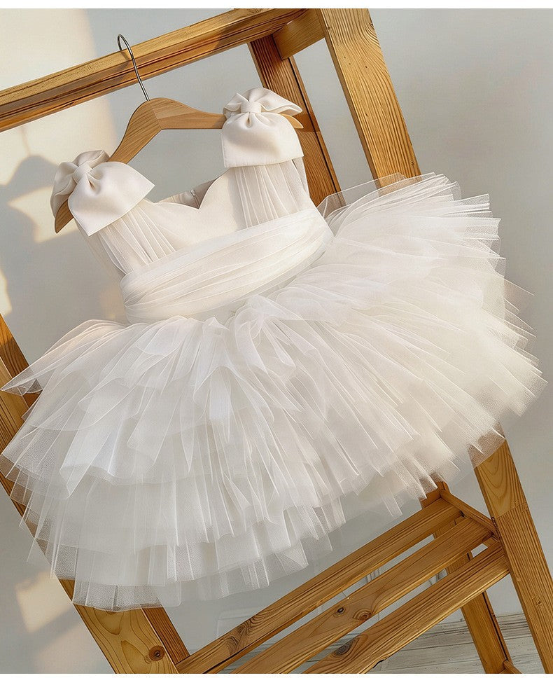 White tulle girls formal dress displayed on a wooden ladder, side angle, for weddings and ceremonies.