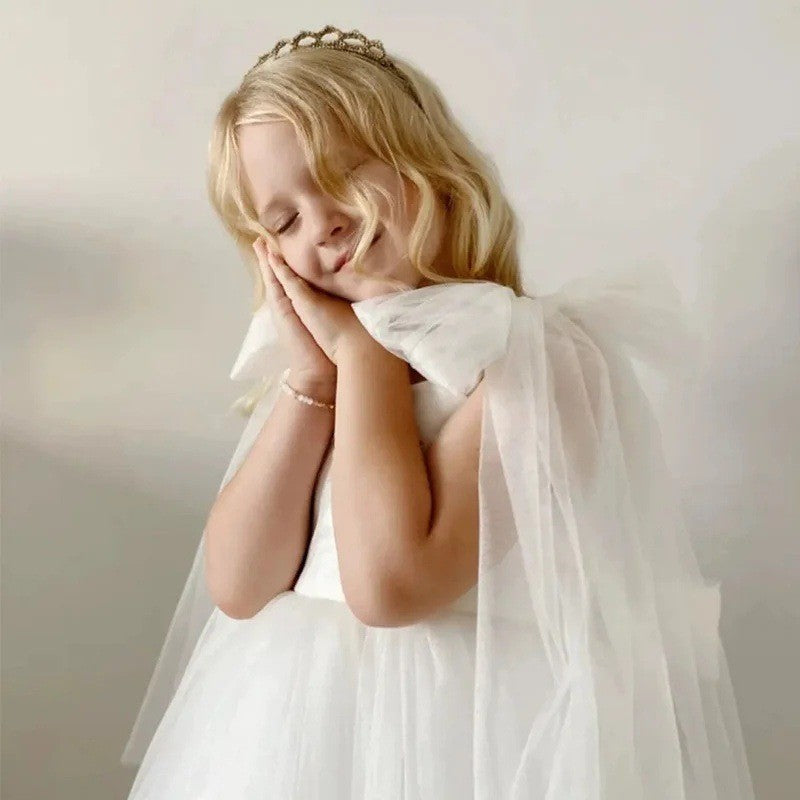 Close-up of the oversized tulle shoulder bow and its streamers on the white dress for girls.