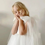 Close-up of the oversized tulle shoulder bow and its streamers on the white dress for girls.