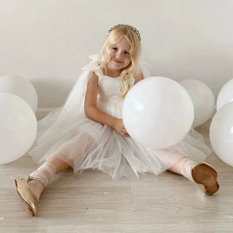Girl sitting in the white tulle girls party dress with the skirt spread around her, for a birthday celebration.