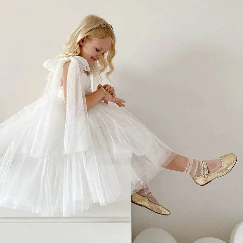 White tulle princess dress for girls with the streamers falling behind, side view, for a ceremony.