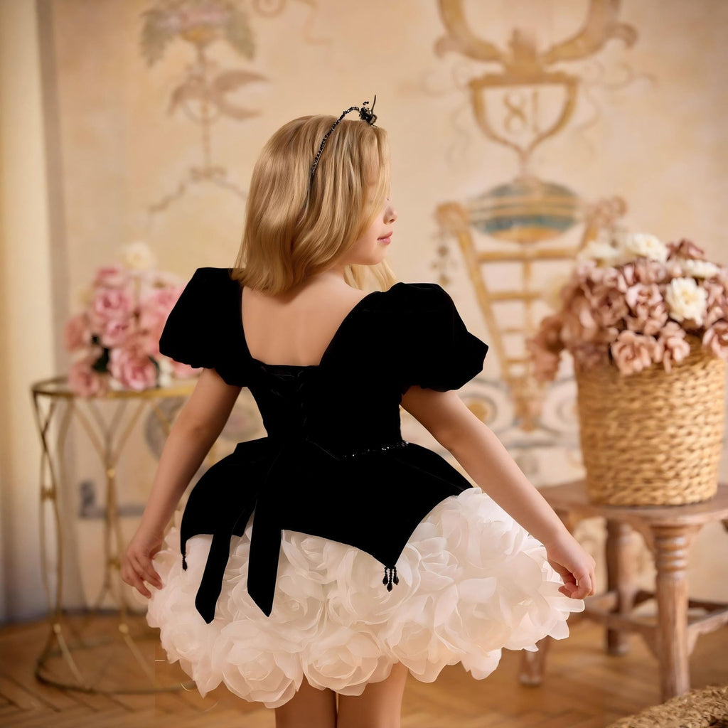 Black and white girls party dress showing the lace-up velvet back, long bow tails and white rosette skirt, back view, for recitals.