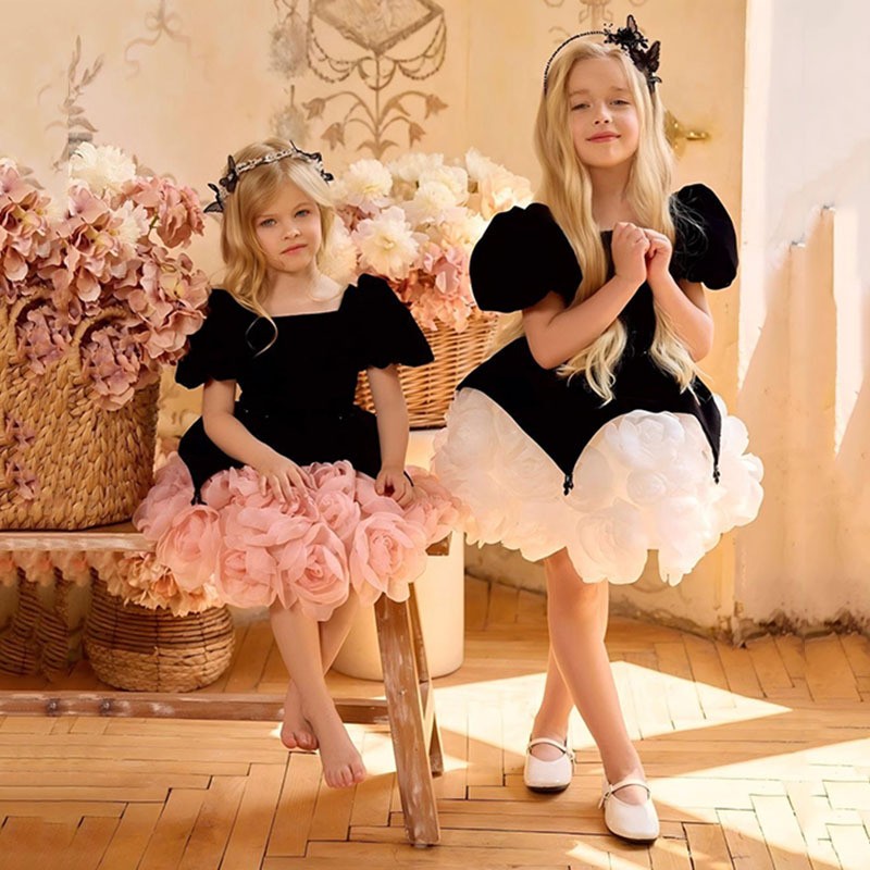 Two black velvet princess dresses for girls, one with a pink and one with a white rosette tutu skirt, lifestyle view for photoshoots.