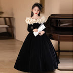 Black velvet princess dress for girls with a cream ruffled collar and full skirt, front view.