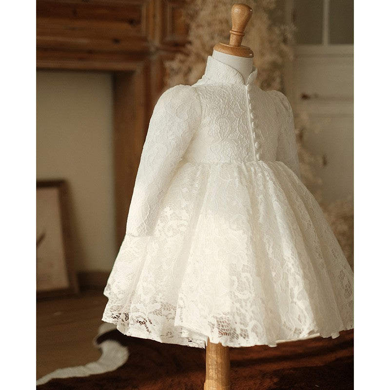 Ivory lace white dress for girls displayed at an angle in a styled room, three-quarter view.