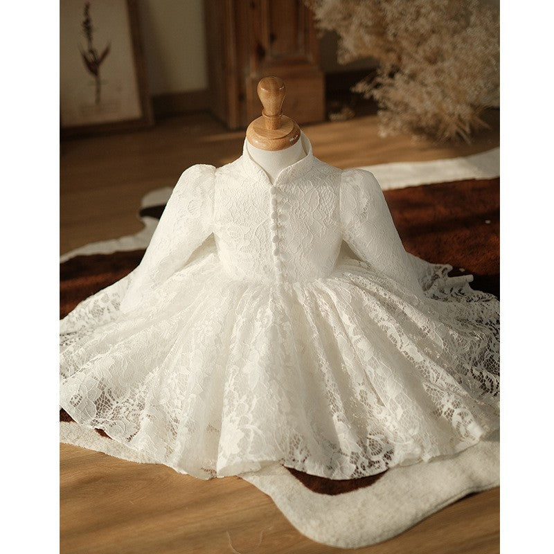 Ivory lace flower girl dress laid out on a rug with the full skirt fanned open, styled scene.