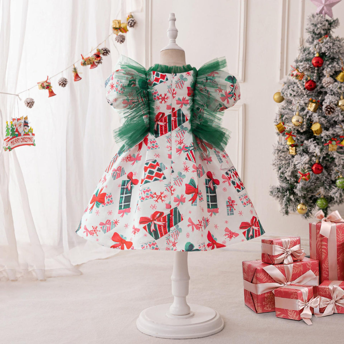 White printed satin girls Christmas dress on a stand with green tulle ruffles and puff sleeves, designed for holiday parties.