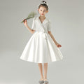 White satin girls dress with a tuxedo lapel collar, puff half sleeves and a full knee-length skirt, designed for weddings and recitals.